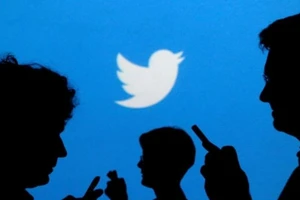 Hình ảnh người dùng điện thoại thông minh ở bên dưới logo mạng xã hội Twitter.
