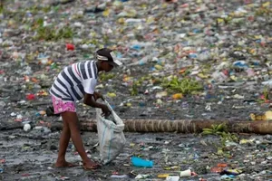 Một người phụ nữ nhặt những chiếc cốc nhựa dọc theo bờ sông Pasig đầy rác thải ở Manila, Philippines, ngày 10-6-2021.