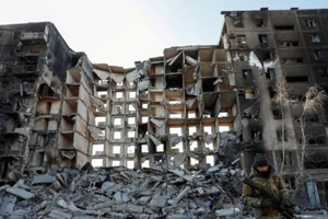 Binh sĩ Nga đứng gác gần một tòa nhà chung cư bị phá hủy ở TP Mariupol, Ukraine, ngày 28-3.