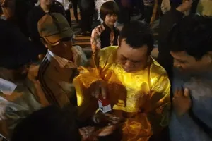 Đóng ấn giả vào tay du khách ở đền Trần trước giờ khai ấn