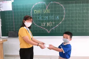 Cô giáo trao khẩu trang do TP trang bị cho học sinh trong ngày quay lại trường. 