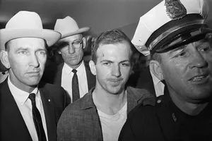 Ông Lee Harvey Oswald (giữa) sau khi bị bắt. Ảnh: THE NEW YORK TIMES