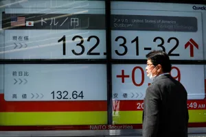 Một người đàn ông nhìn vào bảng tỷ giá hối đoái giữa đồng yên Nhật và USD trên bảng điện ở thủ đô Tokyo (Nhật) ngày 20-3. Ảnh: REUTERS