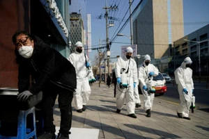 Quân nhân Hàn Quốc mặc đồ bảo hộ đang khử trùng tại tuyến phố thuộc khu vực mua sắm ở Seoul, Hàn Quốc ngày 6-3-2020 - Ảnh: REUTERS