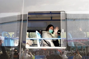 Bệnh nhân COVID-19 bình phục vẫy tay chào nhân viên y tế khi xuất viện tại Vũ Hán, tỉnh Hồ Bắc (Trung Quốc). Ảnh: TÂN HOA XÃ