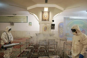 Xịt khử trùng tại một ngôi đền ở Iran - Ảnh: REUTERS