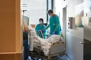 Một người lính Thụy Sĩ (phải) giúp di chuyển giường bệnh nhân tại Bệnh viện Pourtales ở Neuchatel, sau khi Thụy Sĩ triển khai quân đội vào chống COVID-19. Ảnh: AFP