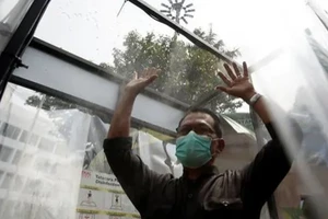 Một người đàn ông đeo khẩu trang vào buồng xịt khử trùng bên ngoài trung tâm mua sắm ở thủ đô Jakarta (Indonesia). Ảnh: REUTERS