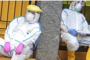 Hai nhân viên y tế Indonesia nghỉ mệt sau khi xét nghiệm cho một nhóm người ở thành phố Depok, Indonesia. Ảnh: REUTERS