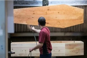 Một công nhân đang phủ vecni cho quan tài. Ảnh: AFP