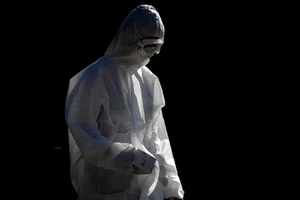 Một người dân mặc trang phục bảo hộ đi bộ gần gần Công viên St James, ở thành phố Newcastle, Anh. Ảnh: REUTERS