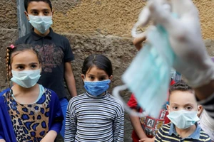 Chú hề Ahmed Naser đang biểu diễn các trò vui nhộn để khuyến khích trẻ em mang khẩu trang, nhằm hạn chế lây nhiễm COVID-19 tại khu vực quận Darb Al-Ban, thủ đô Cairo, Ai Cập. Ảnh: REUTERS