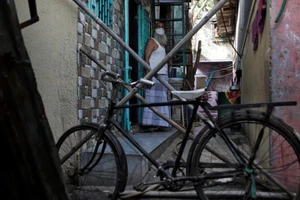 Một người dân ở khu Dharavi dùng xe đạp và gậy gộc để chắn đường, ngăn không cho người lạ vào khu vực nhà mình, nhằm hạn chế lây lan COVID-19. Ảnh: REUTERS