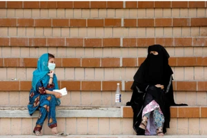 Một phụ nữ và một bé gái Pakistan giữ khoảng cách an toàn khi đang ngồi đợi kết quả xét nghiệm COVID-19 tại một điểm xét nghiệm ở thành phố Karachi, Pakistan. Ảnh: REUTERS