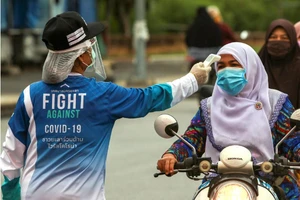 Một phụ nữ được đo nhiệt độ tại một điểm kiểm soát ở tỉnh Yala, Thái Lan. Ảnh: REUTERS