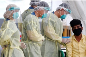 Nhân viên y tế lấy mẫu xét nghiệm cho một công nhân nhập cư tại ký túc xá ở Singapore ngày 15-5. Ảnh: REUTERS 