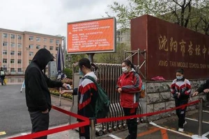 Học sinh ở TP Thẩm Dương đang đợi để đo thân nhiệt trước khi vào lớp ngày 20-4. Ảnh: AFP 