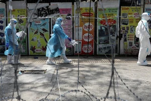 Nhân viên y tế đi ngang qua một khu vực đỏ (khu vực có nguy cơ lây nhiễm cao) được rào kẽm gai ở thành phố Petaling Jaya, Malaysia. Ảnh: REUTERS