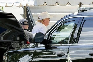 Tổng thống Trump đội mũ lưỡi trai và mặc áo phông trắng đi chơi golf. Ảnh: BLOOMBERG