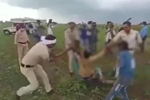 Hình ảnh cắt từ video cho thấy nhiều cảnh sát đang tấn công hai nông dân người Dalit. Ảnh: CNN