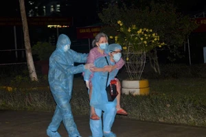 Nhân viên y tế cõng một cụ bà vào khu cách ly của quân đội tại Đà Nẵng. Ảnh: HẢI HIẾU