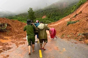 Dùng cáng khiêng sản phụ sắp sinh lên xe múc để chở qua vùng sạt lở