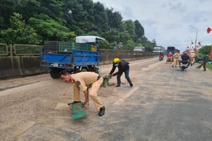 Lực lượng CSGT Đồng Nai quét dọn gỗ vụn rơi vãi trên quốc lộ 1