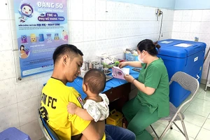 Người dân đưa trẻ đến Trạm y tế phường 8, quận Gò Vấp để tiêm vaccine trong chương trình tiêm chủng mở rộng.