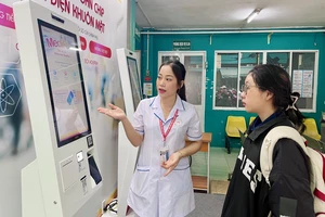 Điều dưỡng Nguyễn Thị Thu hướng dẫn bệnh nhân đăng ký khám bệnh bằng ki-ốt thông minh tại BV quận Phú Nhuận. Ảnh: THẢO PHƯƠNG