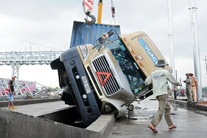 Xe container ‘vấp’ dải phân cách lật nghiêng, 13 tấn bánh ngập nước