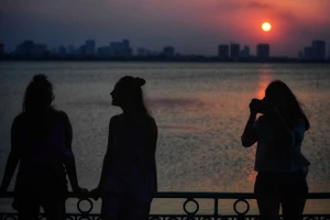 Hai phụ nữ người Nam Phi (trái) đứng bên Hồ Tây vào thời điểm hoàng hôn. (Ảnh: zingnews.vn)