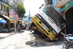 Xe tải sụp hố ga lật chổng vó giữa phố Sài Gòn