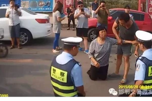 Cảnh sát giao thông quỳ xuống đất để giải thích cho dân