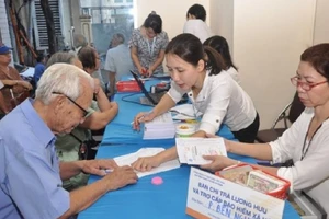 Nhân viên bưu điện chi trả lương hưu cho người dân. Ảnh: V.LONG