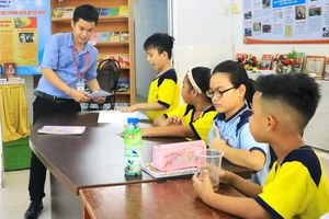 Thầy Lê Tấn Phát trong giờ dạy miễn phí cho các em nhỏ tại xóm trọ công nhân ở quận 4. Ảnh: VÕ THƠ