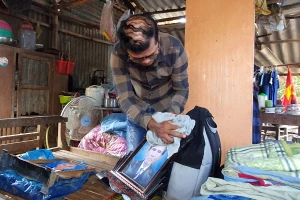 Anh Trương Văn Hải lắp lại di ảnh của cha đã bạc màu vì thấm nước mưa.