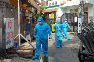 Anh Hoàng Phương Sinh (giữa), thành viên tổ cấp cứu cộng đồng, hỗ trợ Thiếu tá - BS Tạ Văn Mạnh đến thăm khám cho người dân.