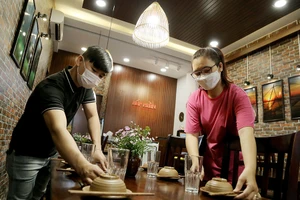 Nhân viên một nhà hàng ở quận Gò Vấp (TP.HCM) sửa soạn các bàn ăn chờ được phục vụ khách ăn uống tại chỗ trở lại vào chiều 25-10.