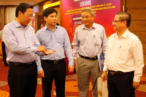 Chủ tịch UBND TP.HCM Phan Văn Mãi (bìa trái) trao đổi cùng Chủ tịch UBND TP Cần Thơ Trần Việt Trường (bìa phải) và các đại biểu bên hành lang hội nghị.