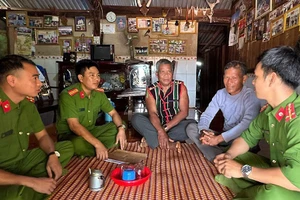 Già làng Điểu Mpiăr (giữa) trò chuyện với cán bộ công an.
