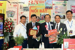 Ông Mai Ngọc Phước, Tổng Biên tập báo Pháp Luật TP.HCM (giữa), chụp ảnh cùng các đại biểu tham quan gian trưng bày báo Pháp Luật TP.HCM, tại Hội Báo toàn quốc 2025.