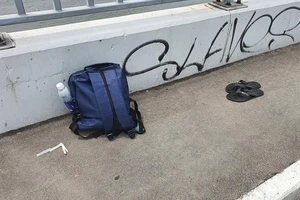 Một nam thanh niên nhảy cầu Sài Gòn sau khi để lại ba lô và dép trên thành cầu trong tuần qua. Ảnh: NGUYỄN YÊN