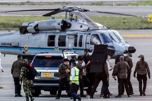 Tổng thống Colombia Ivan Duque (áo trắng, thứ 4 từ phải sang) và các vệ sĩ đứng gần chiếc trực thăng bị trúng đạn hôm 25-6. Ảnh: AFP