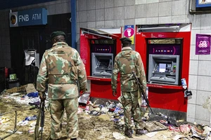ực lượng an ninh bên cạnh hai trụ ATM đã bị đám đông bạo loạn đập phá ở TP Johannesburg (Nam Phi). Ảnh: AP