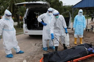 Nhân viên y tế Malaysia khử trùng thi thể bệnh nhân COVID-19 trước khi mai táng. Ảnh: THE STRAITS TIMES