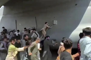 Người dân Afghanistan cố "đu bám" một máy bay quân sự Mỹ khi máy bay đang cất cánh từ sân bay Kabul hôm 16-8. Ảnh: AP