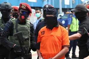 Một phần tử Hồi giáo cực đoan (áo cam) bị cảnh sát Indonesia bắt hồi tháng 12-2020 vì bị nghi liên quan nhiều vụ khủng bố từ những năm 2000. Ảnh: AP