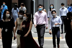 Người dân Singapore duy trì việc đeo khẩu trang và dần khôi phục cuộc sống thường nhật khi nước này chọn "sống chung với COVID-19". Ảnh: REUTERS