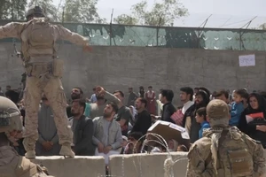 Một gia đình người Afghanistan đủ điều kiện được hộ tống ra máy bay di tản ở sân bay Kabul ngày 20-8. Ảnh: AFP