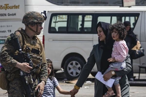 Một lính Mỹ hộ tống một gia đình người Afghanistan ra sân bay Kabul ở thủ đô Kabul ngày 20-8. Ảnh: AP